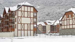 Een traditioneel gebouw in chaletstijl met een hellend dak, houten balkons en een berg in de achtergrond bedekt met sneeuw.