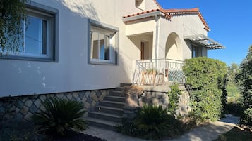 A two-story house with a balcony, a stone staircase, and a well-maintained garden.