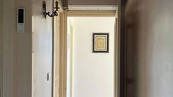 A hallway with a wooden ceiling, a radiator, and a tiled floor leading to a room with a door.