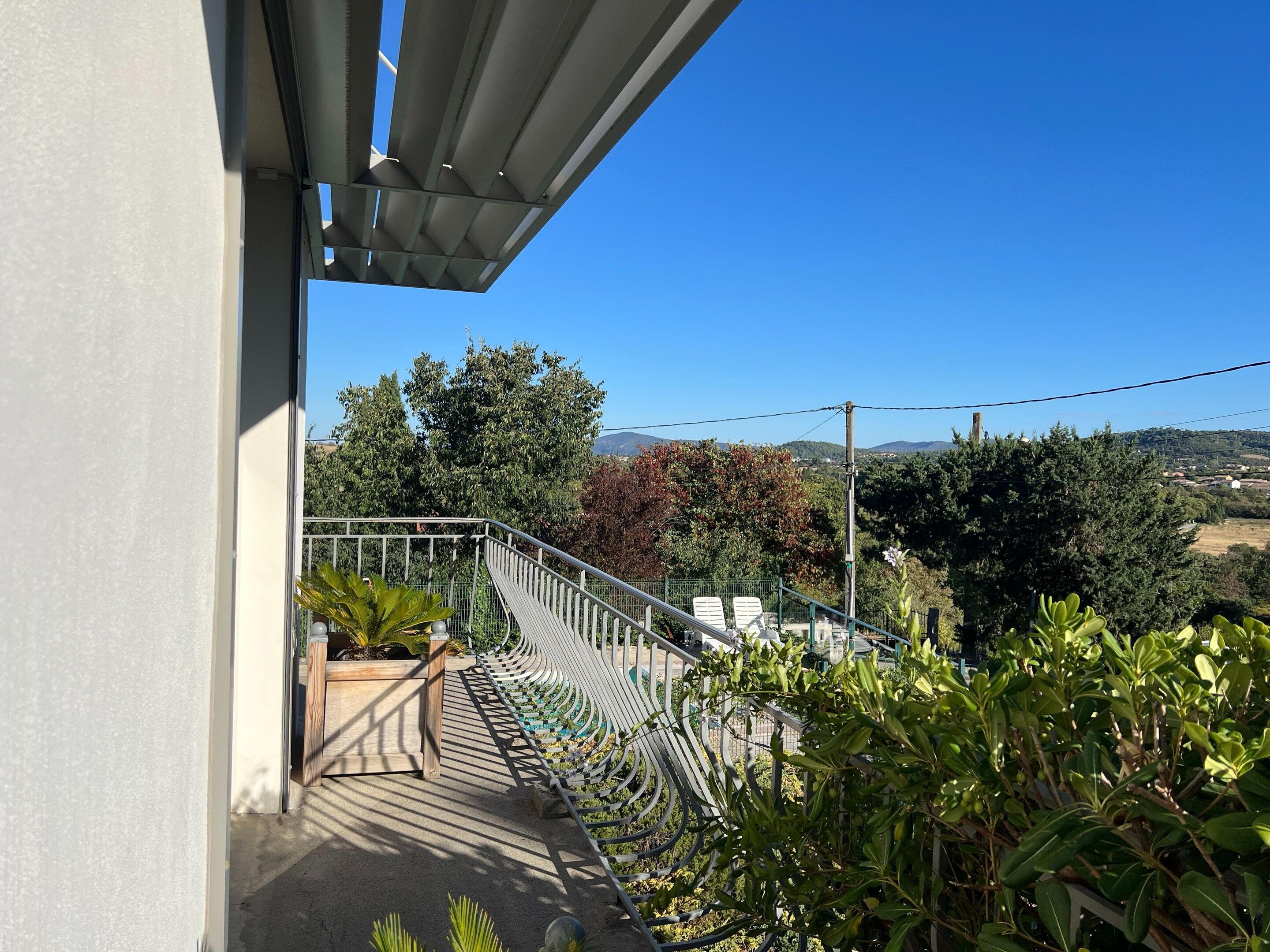 A balcony with a view of a garden and distant landscape.