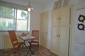 Un coin repas comprenant une table, des chaises et une fenêtre avec des stores.