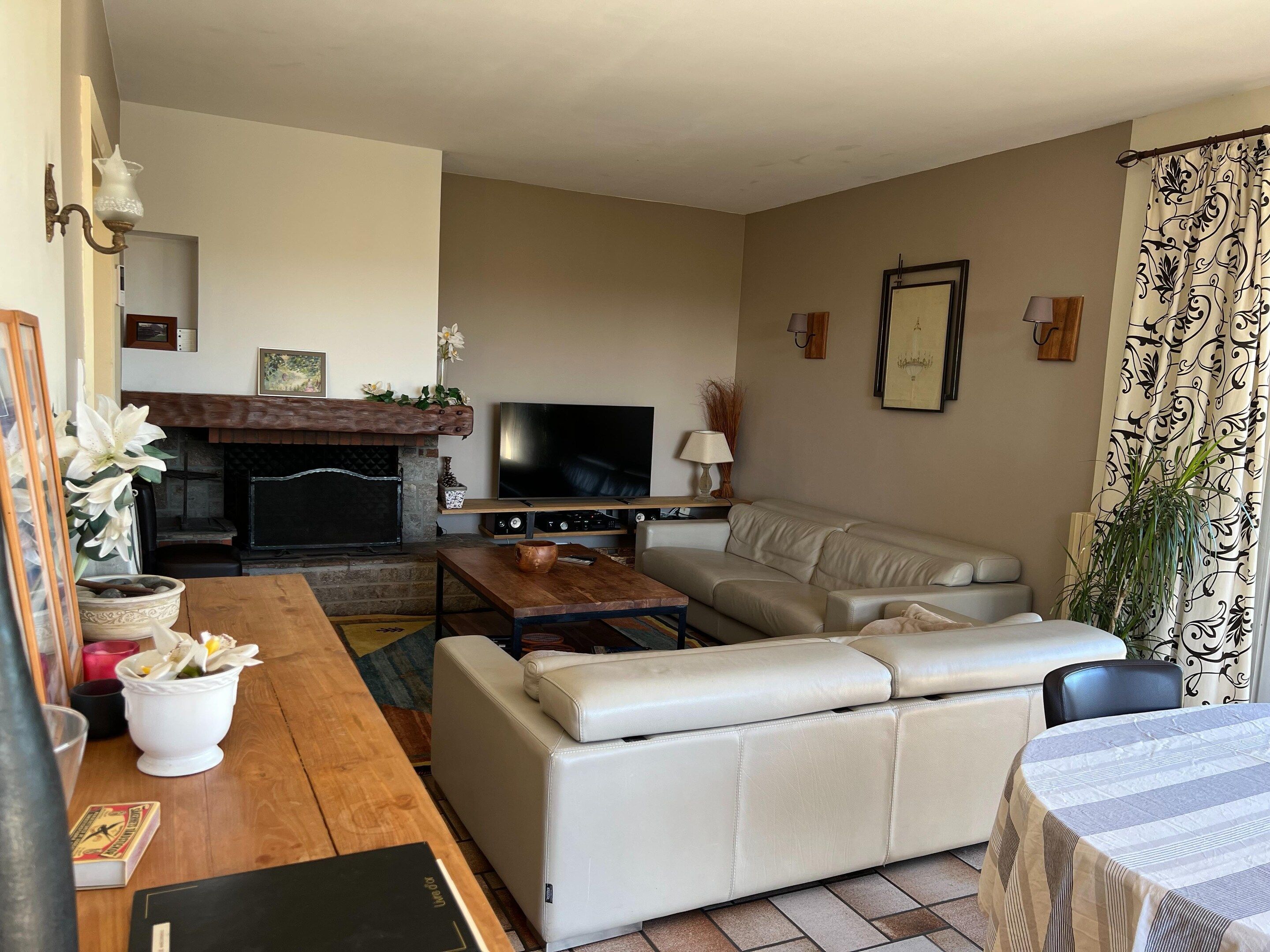 A living room with a fireplace, a sofa, a television, and a dining table.