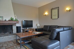 Ein Wohnzimmer mit Kamin, Fernseher, Sofa und Couchtisch.