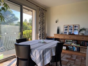 A dining area with a table, chairs, a bookshelf, and a view through a glass door. - Spacious Villa Retreat in Carcassonne (Carcassonne)