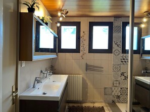 Un baño moderno con dos lavamanos, ducha y baldosas decorativas.