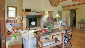 Una cocina rústica con vigas de madera, chimenea y una mesa de comedor con sillas.