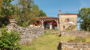 Una casa de piedra con techo de tejas, un muro de piedra y un porche cubierto.