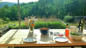 Mesa de comedor al aire libre con vistas a un área boscosa.
