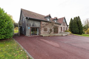 A two-story building with a red-tiled roof, a stone facade, and a paved driveway. - Mountain Stay Near Canal (Niderviller)