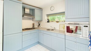 A kitchen with light blue cabinets, a stainless steel stove, a sink, and a microwave. - Superb Villa in the Woods of Gaasterland With Wifi and Fireplace (Oudemirdum)