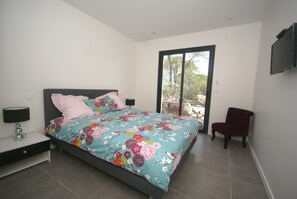 A bedroom with a bed, a chair, a TV, and a window. - Villa in Vidauban With Private Pool (Vidauban)