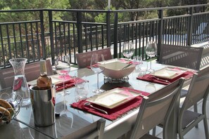 A dining table set with plates, glasses, and cutlery, surrounded by chairs, on a balcony with a railing. - Villa in Vidauban With Private Pool (Vidauban)