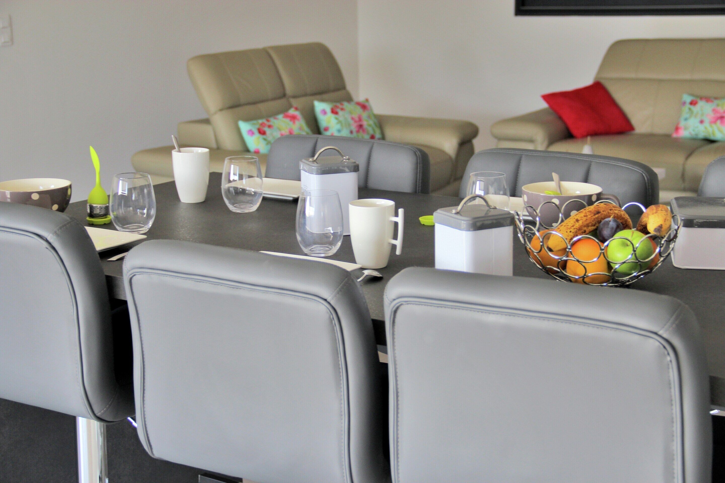 A dining area with a table set for four, including a fruit bowl, glasses, and a pitcher.