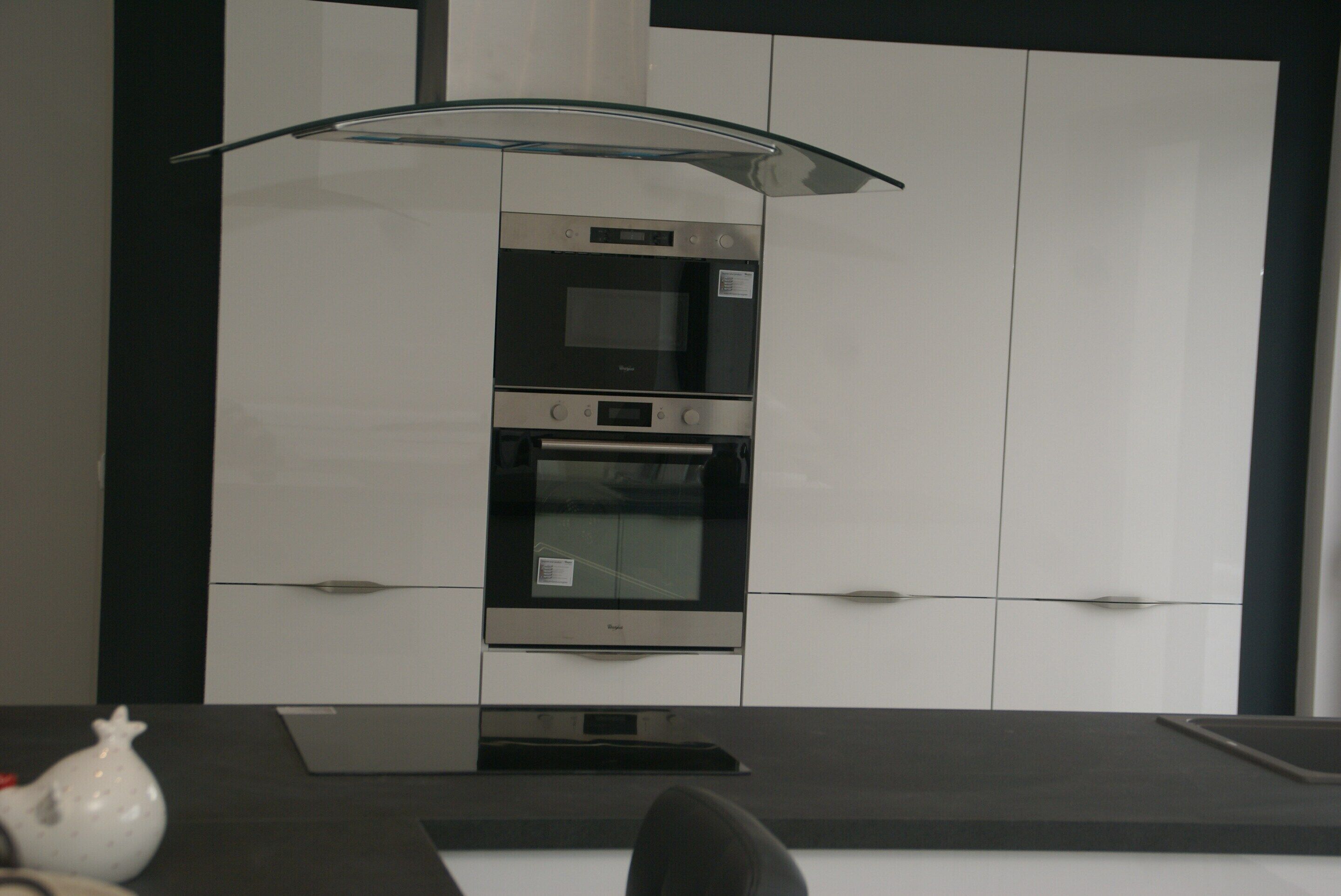 Een moderne keuken met een ingebouwde oven en magnetron, een glazen afzuigkap en witte keukenkastjes.