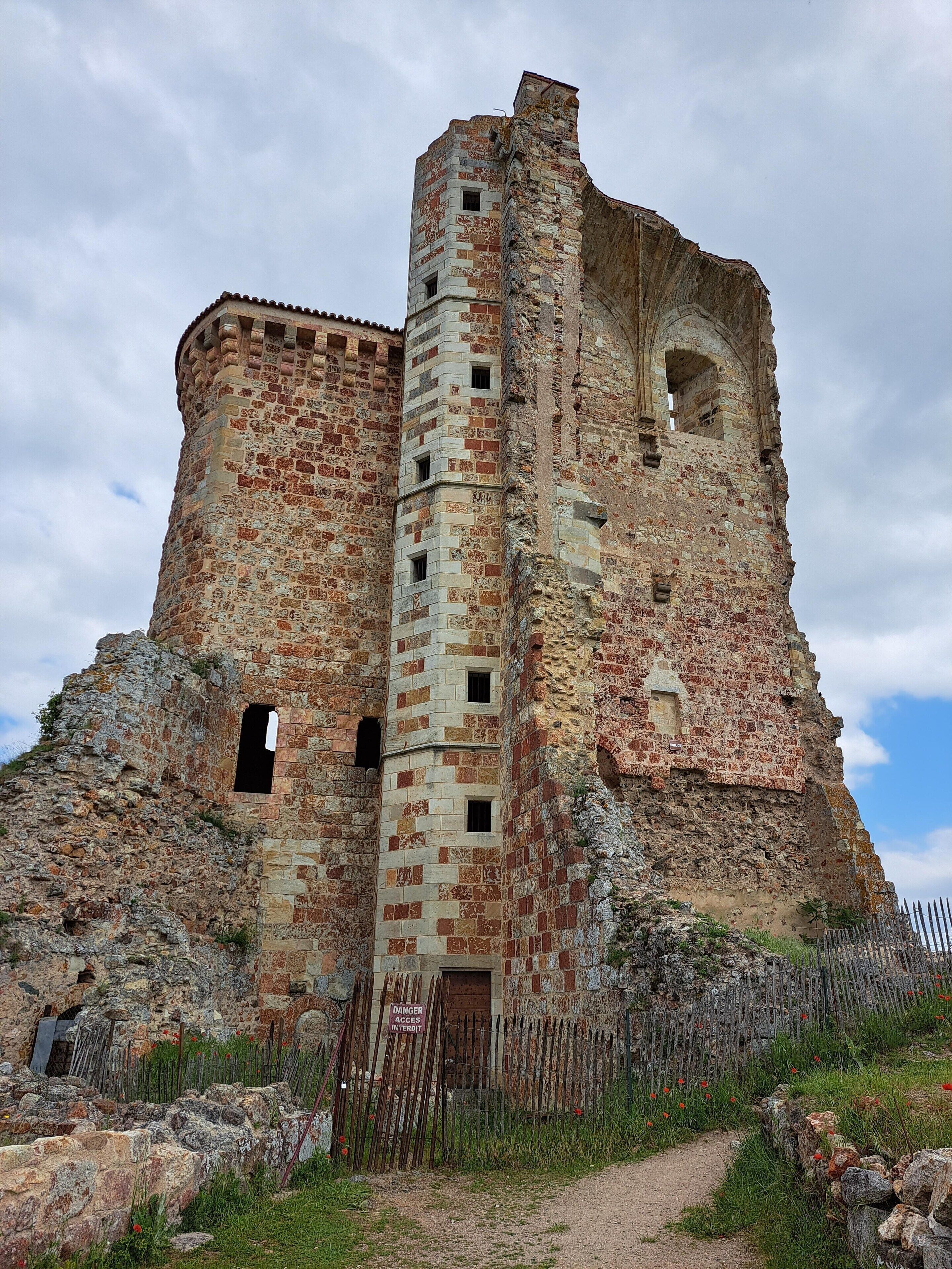 A historic stone castle with a central tower, a fortified entrance, and a surrounding stone wall.