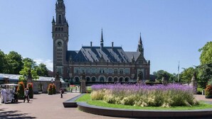 A historic building with a clock tower and a central courtyard with flowers. - Sun-drenched Beachside Apartment in Scheveningen (The Hague)