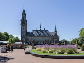 A historic building with a clock tower and a central courtyard with flowers. - Sun-drenched Beachside Apartment in Scheveningen (The Hague)