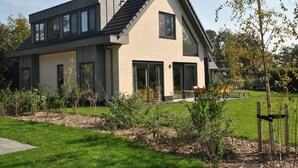 A modern two-story house with a sloped roof, large windows, and a well-maintained garden. - Bungalow in Texel Near National Park Dunes (De Koog)