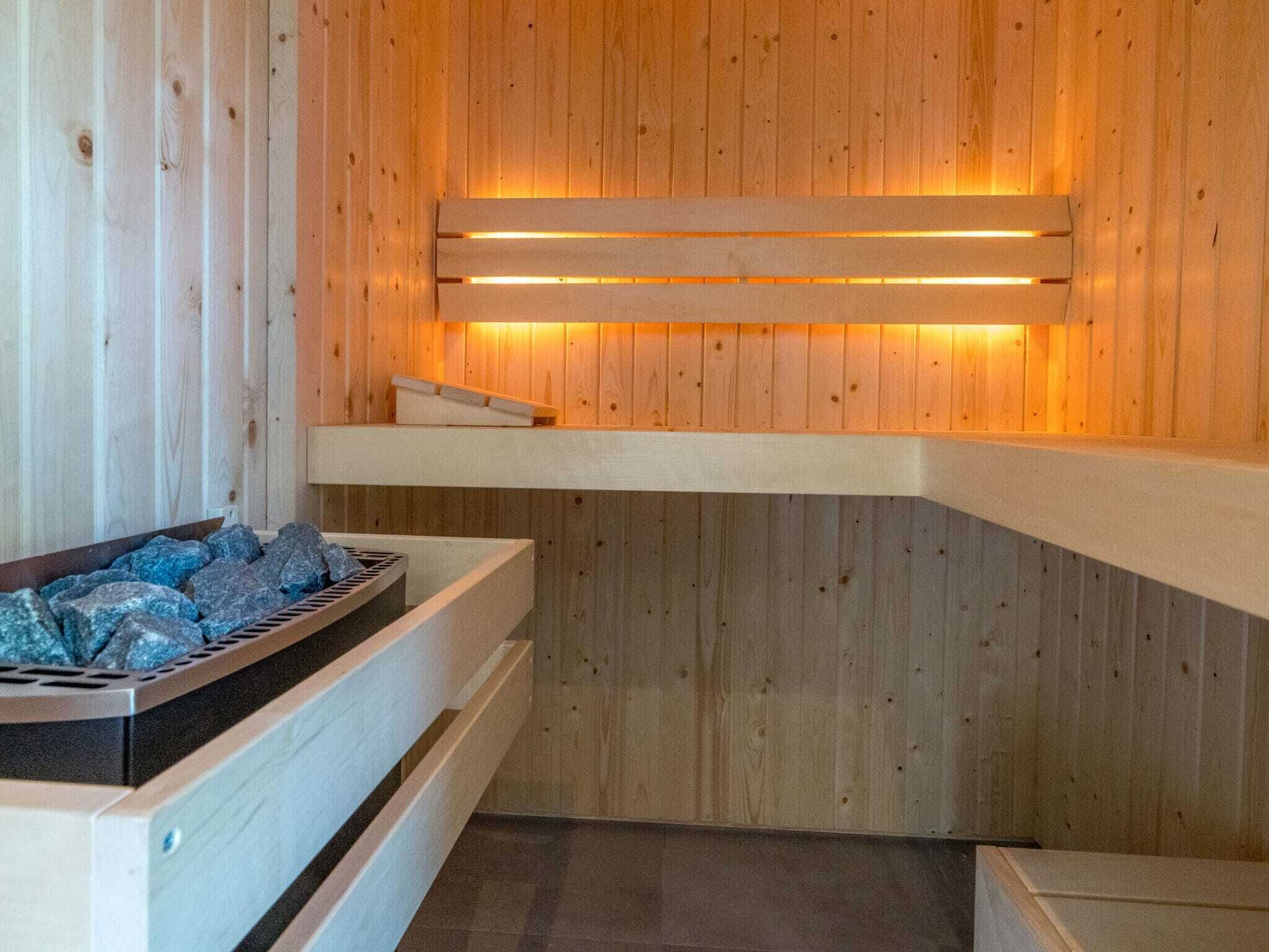 Eine Holzsauna mit Bänken und einer erwärmten Wand.