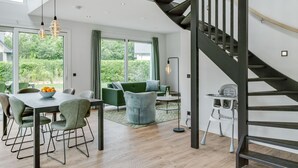 A modern interior with a dining area, green sofas, and a staircase. - Bungalow in Texel Near National Park Dunes (De Koog)
