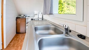 A kitchen with two stainless steel sinks, a coffee maker, and a refrigerator.