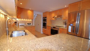 A modern kitchen with granite countertops, stainless steel appliances, and wooden cabinets. - Pochet Association - Nauset Beach Access - Central Air (2161) (Orleans)