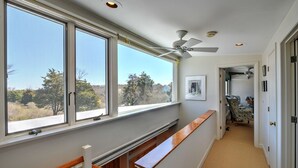 A hallway with large windows, a ceiling fan, and a view of trees outside. - Pochet Association - Nauset Beach Access - Central Air (2161) (Orleans)