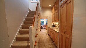 A staircase leading to a kitchen area with wooden cabinets and a tiled floor. - Pochet Association - Nauset Beach Access - Central Air (2161) (Orleans)