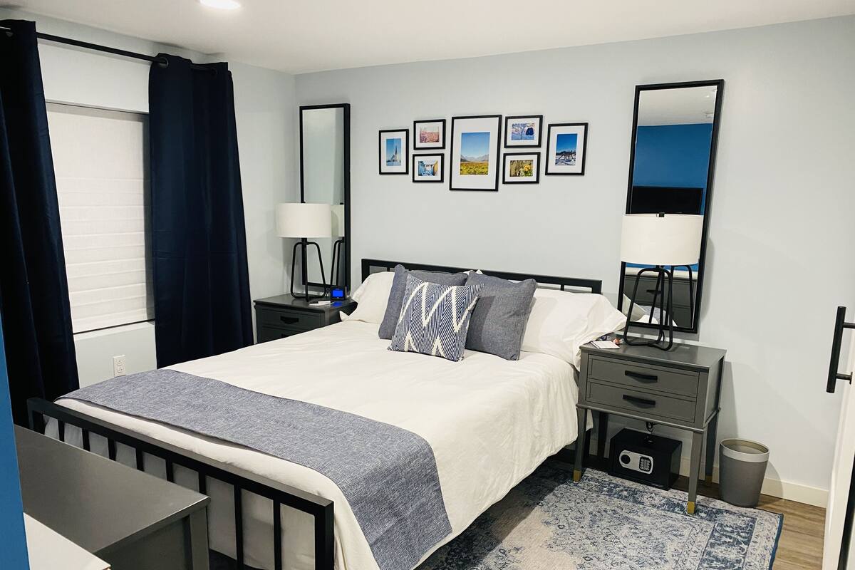 A neatly arranged bedroom with a bed, bedside tables, a desk, and a rug.