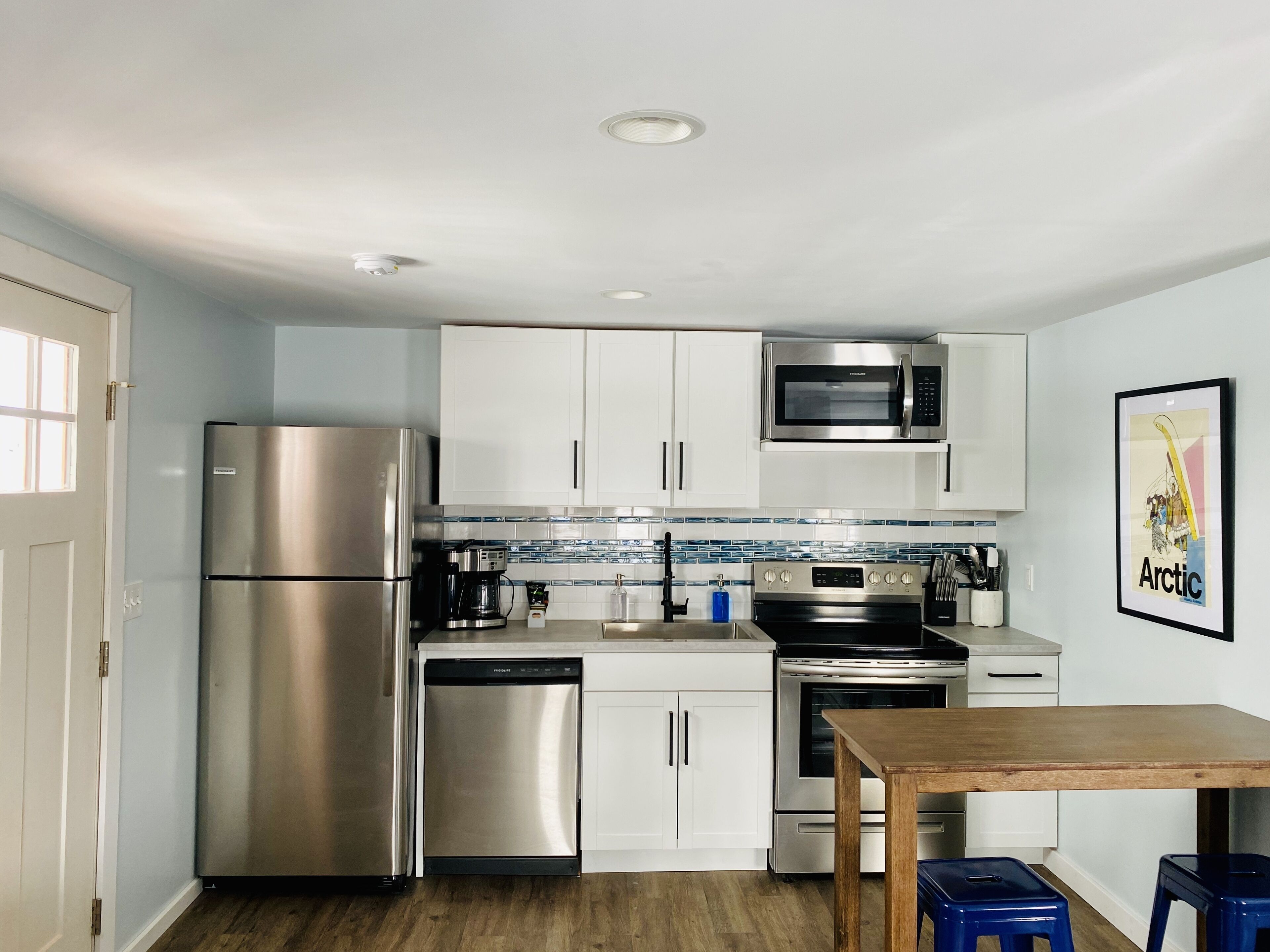 Una cocina moderna con electrodomésticos de acero inoxidable, armarios blancos y salpicadero de azulejos.