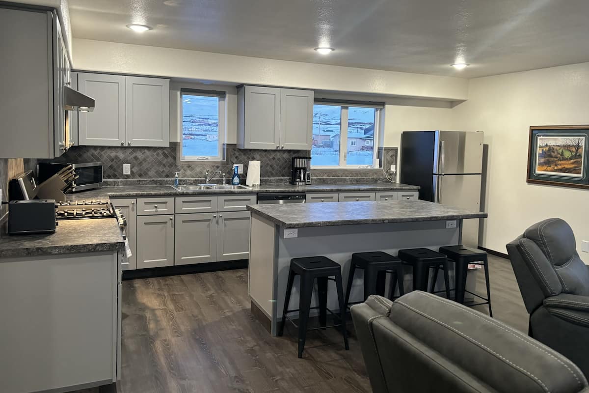 A modern kitchen with white cabinets, a granite countertop, and a central island with bar stools.