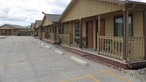 A row of motel-style buildings with individual porches and doors, a parking lot in front, and a clear sky. - Kenedy Country Inn (Kenedy)
