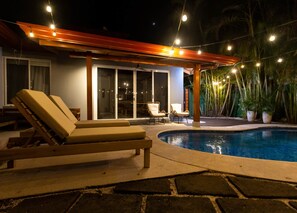 A poolside area with lounge chairs and a covered seating area.