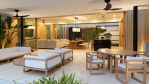 A modern, open-plan living area with a sofa, dining table, and chairs. - Nai'a, Private entrance to Beach, Gated Comunity (Nosara)