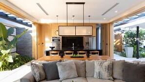 A modern kitchen with a central island, built-in appliances, and pendant lighting. - Nai'a, Private entrance to Beach, Gated Comunity (Nosara)