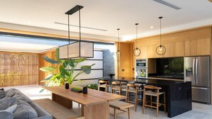 A modern kitchen with a central island, bar stools, and a dining table. - Nai'a, Private entrance to Beach, Gated Comunity (Nosara)