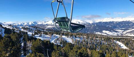 A chairlift in a snowy mountainous area with a clear sky.