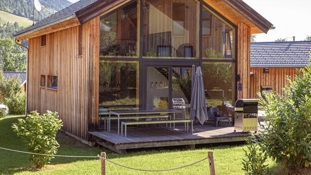 A wooden cabin with large windows, a deck, and outdoor seating. - Superior Chalet at Kreischberg (Sankt Georgen am Kreischberg)