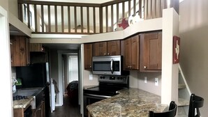 A compact kitchen with wooden cabinets, a built-in microwave, and a granite countertop.
