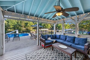 An outdoor patio with a covered seating area, a pool, and umbrellas.