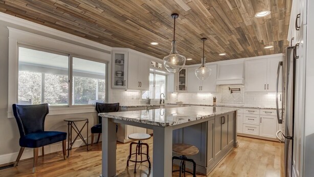 A modern kitchen with a wooden ceiling, white cabinets, a marble island, and bar stools. - Lake Norman Luxury - Large Saltwater Pool, Dock & Boathouse - Sleeps 18 (Denver)