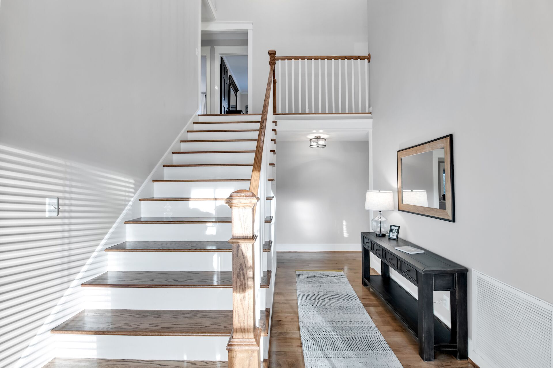 A staircase with wooden steps and a wooden handrail, leading to an upper floor.
