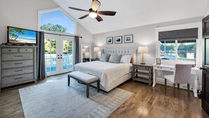 A bedroom with a large bed, a desk, a chair, a ceiling fan, and a view of the outdoors. - Lake Norman Luxury - Large Saltwater Pool, Dock & Boathouse - Sleeps 18 (Denver)