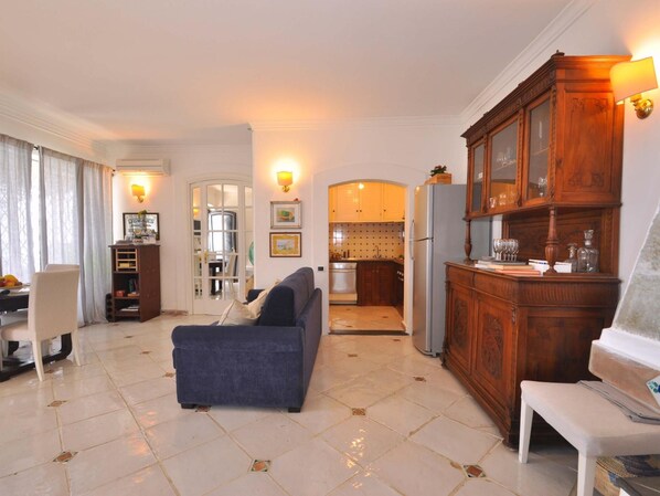 Una sala de estar con un sofá, un comedor con una mesa y una cocina con armarios de madera y un refrigerador.