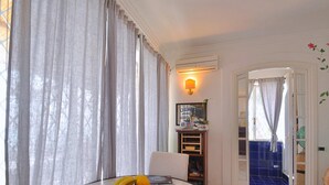 A dining area with a table set for two, featuring a fruit bowl and a magazine. A wall-mounted lamp and a framed picture are visible. - Star Fish House - Two Bedroom Villa, Sleeps 5 (San Cosma)