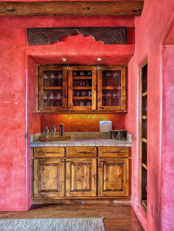 A kitchen with wooden cabinets, a countertop, and a red wall. - Ponderosa Estate | Secluded Luxury (Santa Fe)