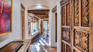 A hallway with a tiled floor, wooden doors with intricate carvings, and a bench with cushions. - Ponderosa Estate | Secluded Luxury (Santa Fe)