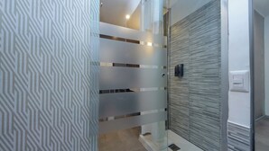Een moderne badkamer met een douchegordijn met geometrisch patroon, een glazen douchecabine en een structuurwand.