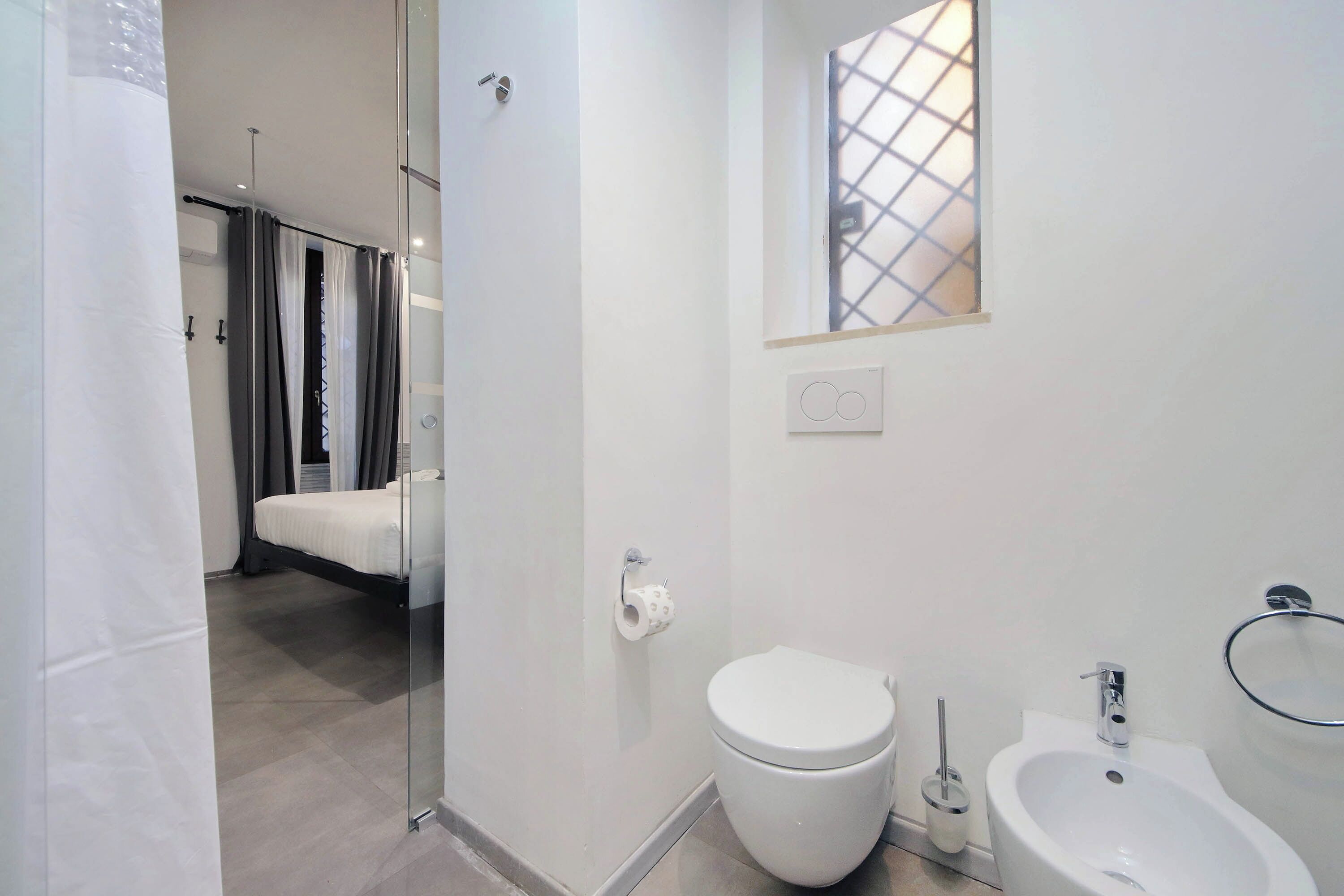 Une salle de bain moderne équipée de toilettes, d’un bidet et d’une douche à parois de verre.