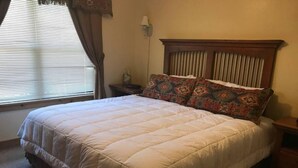 A neatly made bed with a white quilt, a wooden headboard, and patterned pillows.
